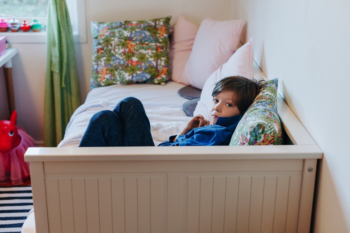 bruke seng som sofa: gutten ligger på en sofa med ryggstøtte