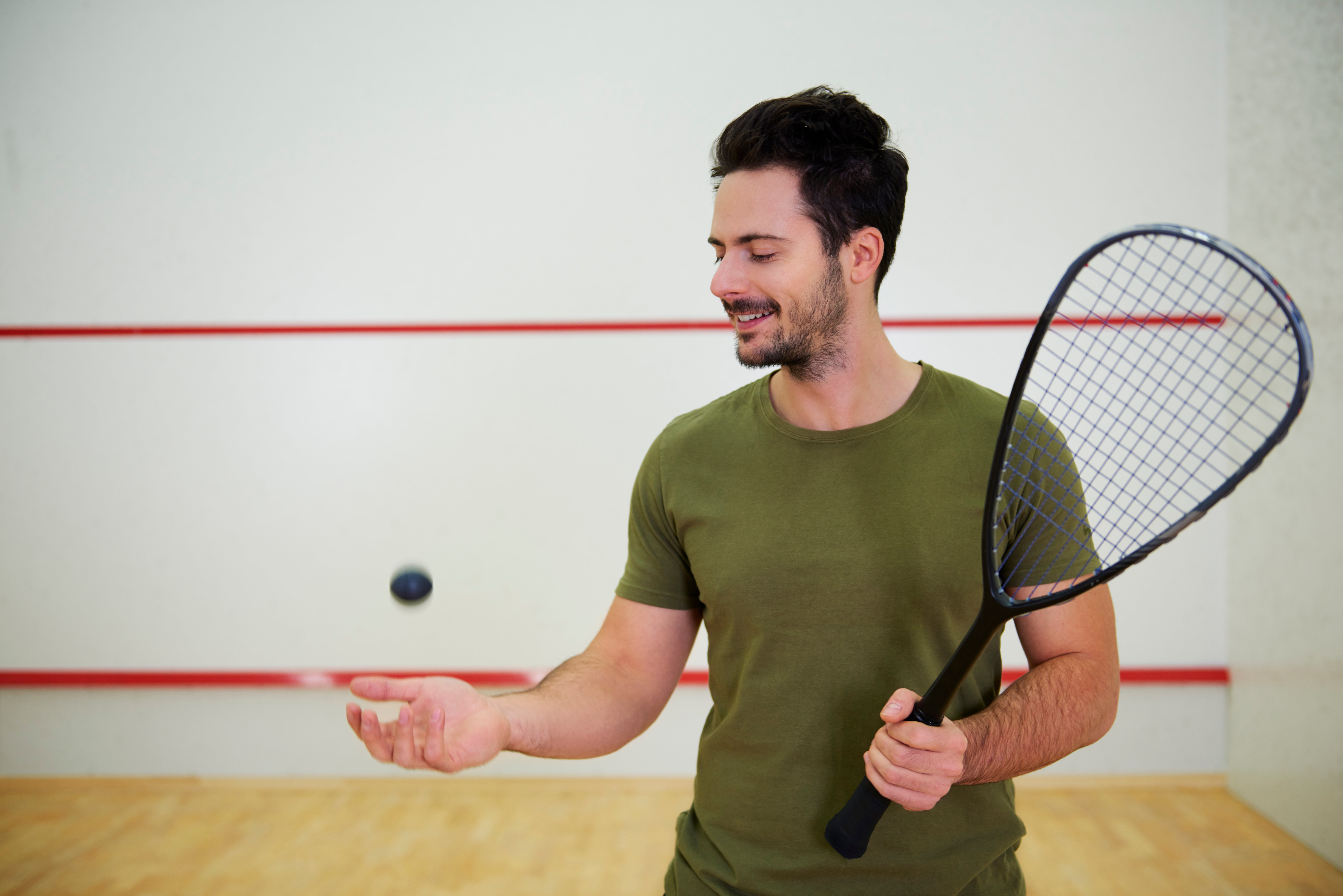 hvordan velge rett squash racket: en mann som holder en palett og en ball for å spille