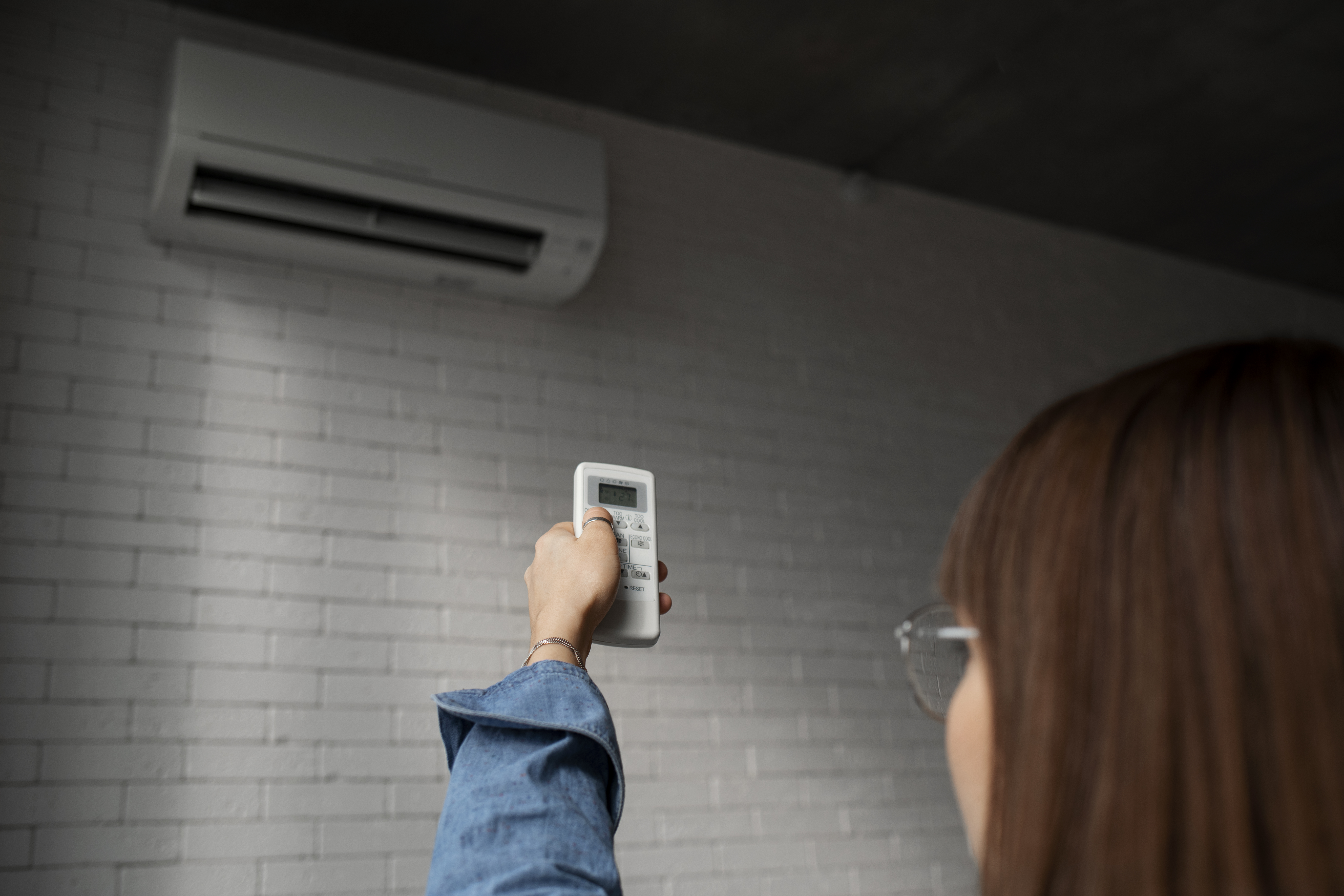 hvordan installere varmepumpe: kvinne som holder en fjernkontroll